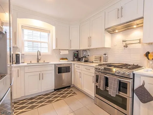 a kitchen with white cabinets appliances and a window