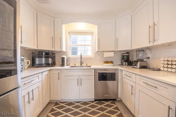 a kitchen with white cabinets appliances and a window