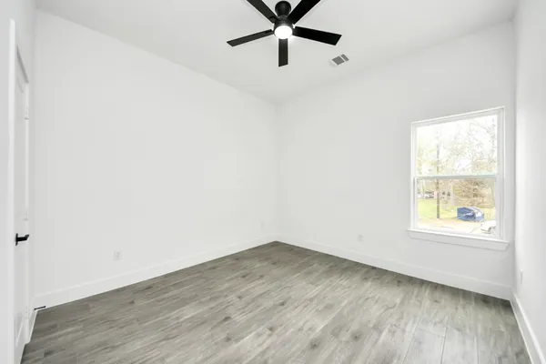 an empty room with wooden floor and windows