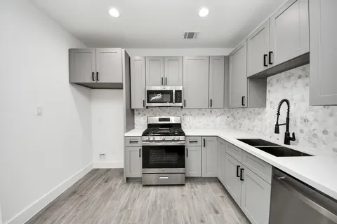 a kitchen with cabinets stainless steel appliances a sink and wooden floor