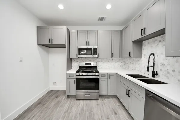 a kitchen with cabinets stainless steel appliances a sink and wooden floor