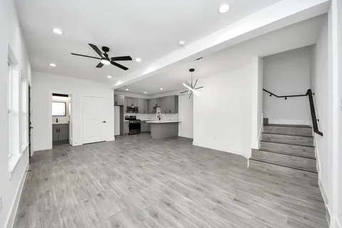 a view of empty room with wooden floor and ceiling fan