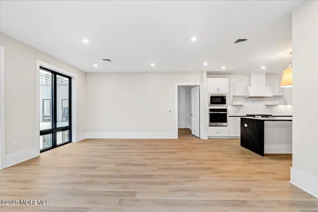 a view of an empty room with wooden floor and outer view
