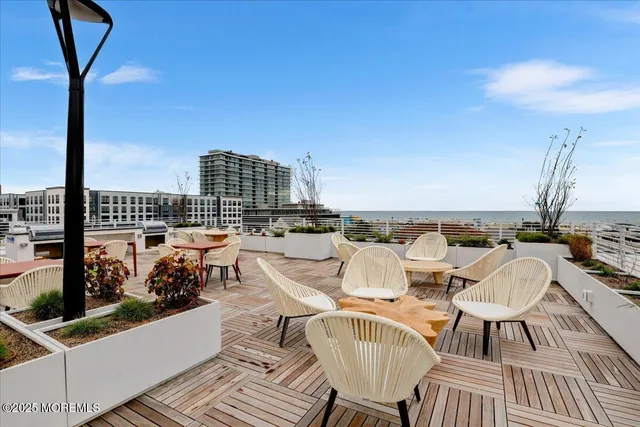 a view of a roof deck with table and chairs with wooden floor and fence