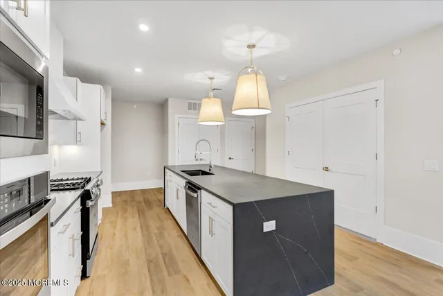 a kitchen with stainless steel appliances granite countertop a sink a stove and a refrigerator