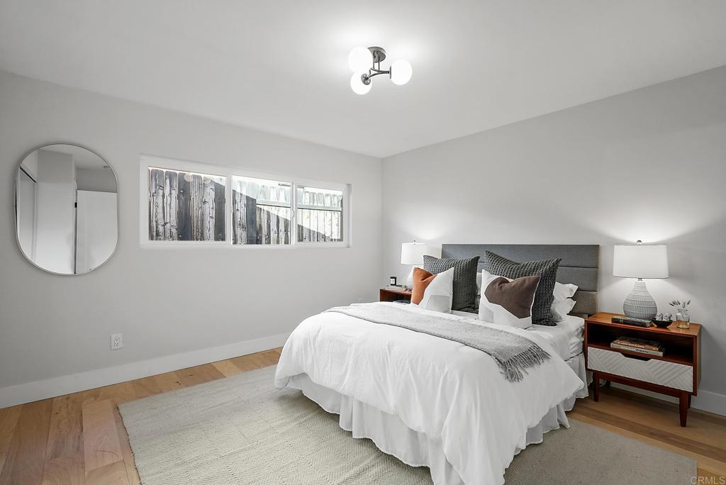 5898 Agee Street San Diego, CA 92122 - Photo 28 of 40 a spacious bedroom with a bed a mirror and lamp