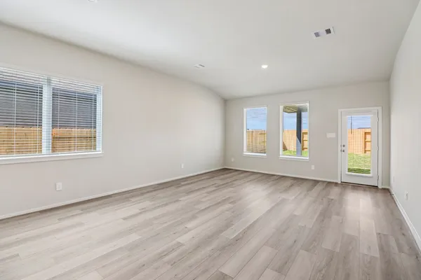 a view of an empty room with wooden floor and windows