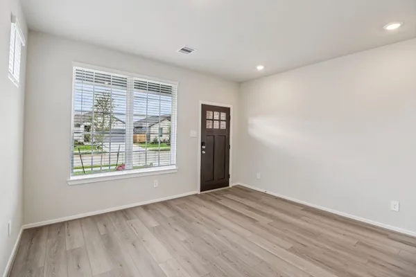 a view of an empty room with wooden floor and a window