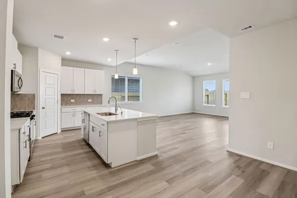 a large kitchen with stainless steel appliances granite countertop a large center island a sink a stove and a refrigerator