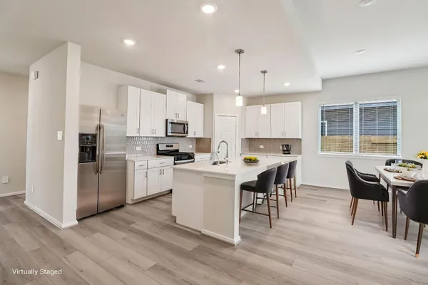 a kitchen with a dining table chairs appliances and cabinets
