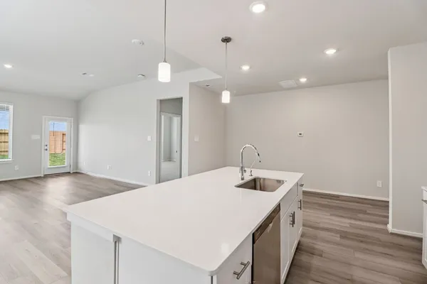 a kitchen with a sink chandelier and wooden floor