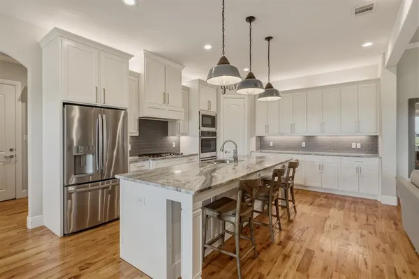 a kitchen with kitchen island granite countertop a sink appliances a counter space and a refrigerator