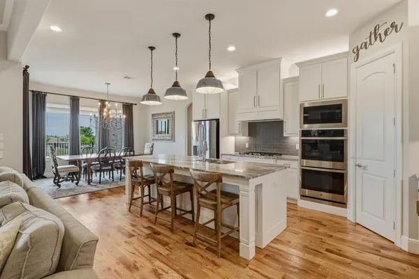 a living room with stainless steel appliances kitchen island granite countertop furniture and a wooden floor