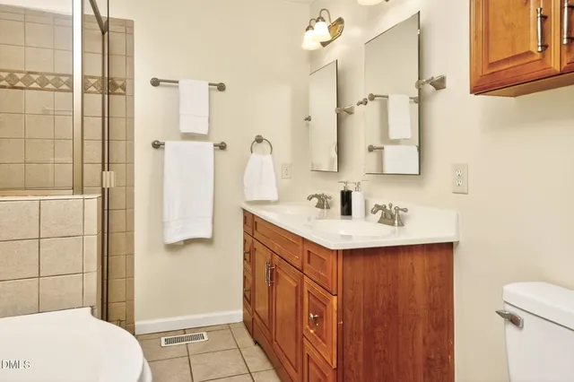 a bathroom with a sink a toilet a mirror and shower