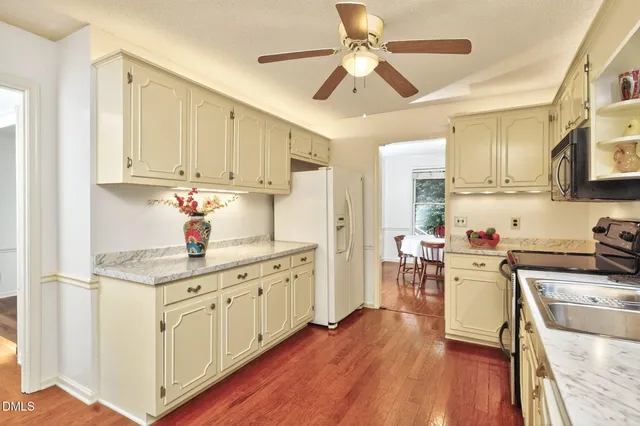 a kitchen with stainless steel appliances white cabinets sink and wooden floor