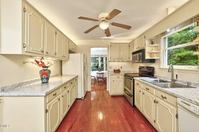 a kitchen with stove a sink dishwasher and a refrigerator with wooden floor