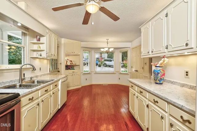 a kitchen with stainless steel appliances granite countertop a sink cabinets and wooden floor