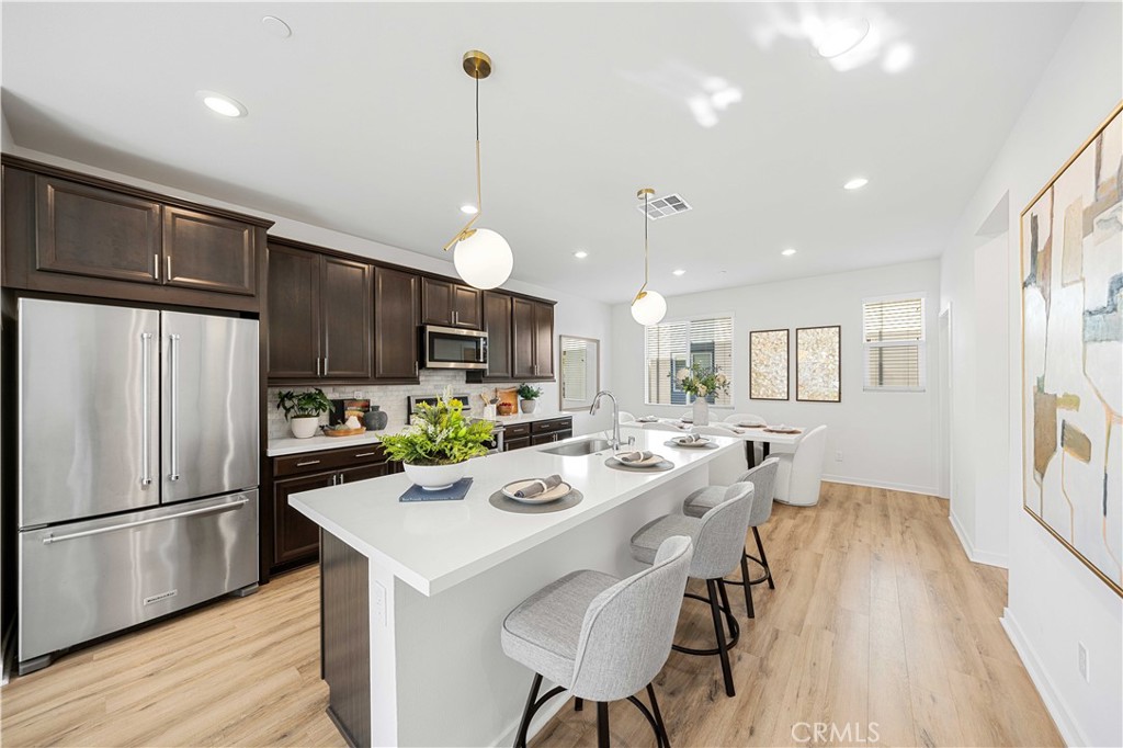 108 Citysquare Irvine, CA 92614 - Photo 14 of 45 a kitchen with stainless steel appliances kitchen island granite countertop a refrigerator a sink dishwasher a stove and white cabinets with wooden floor