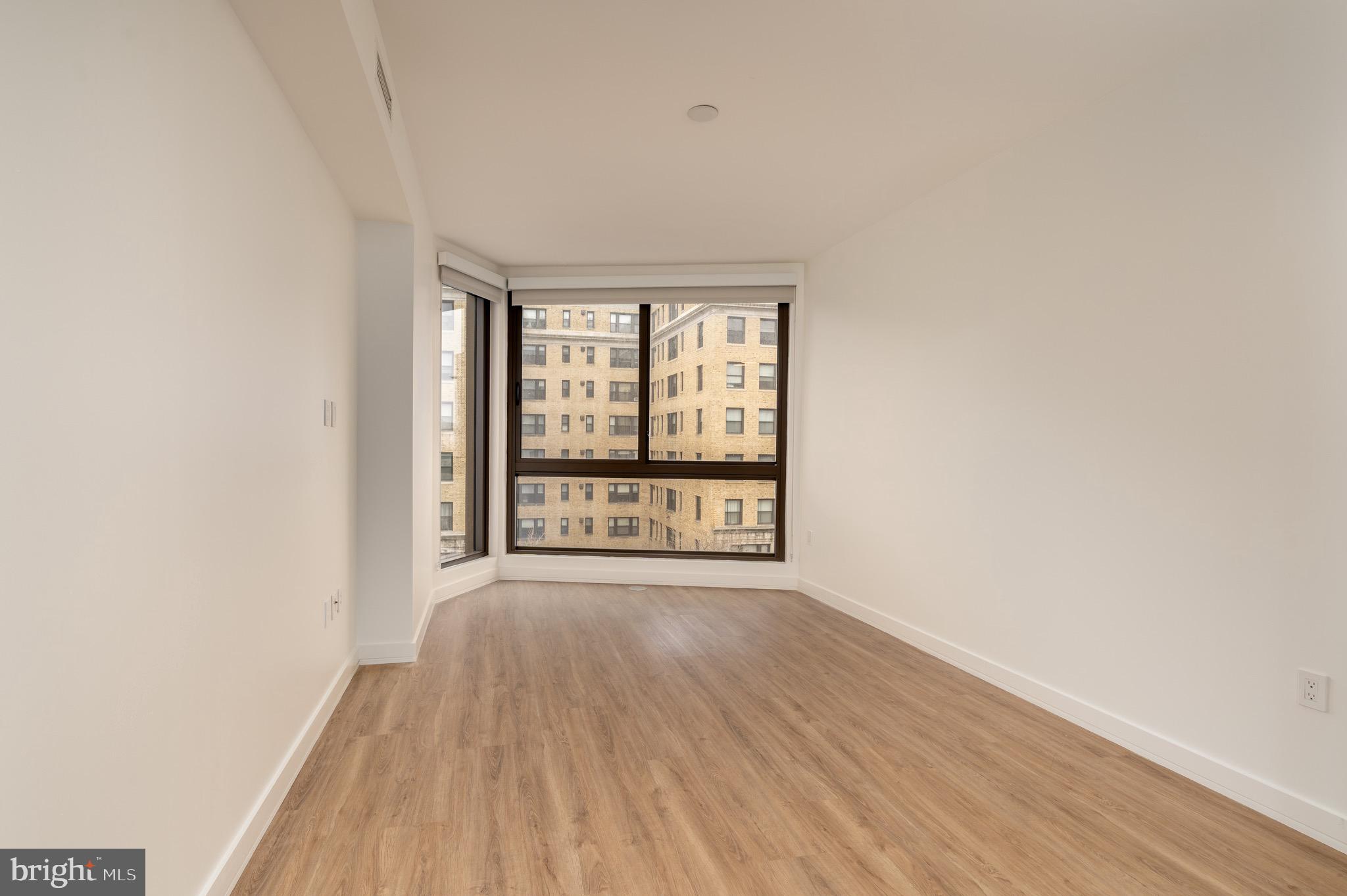 1630 Columbia Road Northwest, Unit 513 Washington, DC 20009 - Photo 4 of 22 a view of an empty room with wooden floor and a window