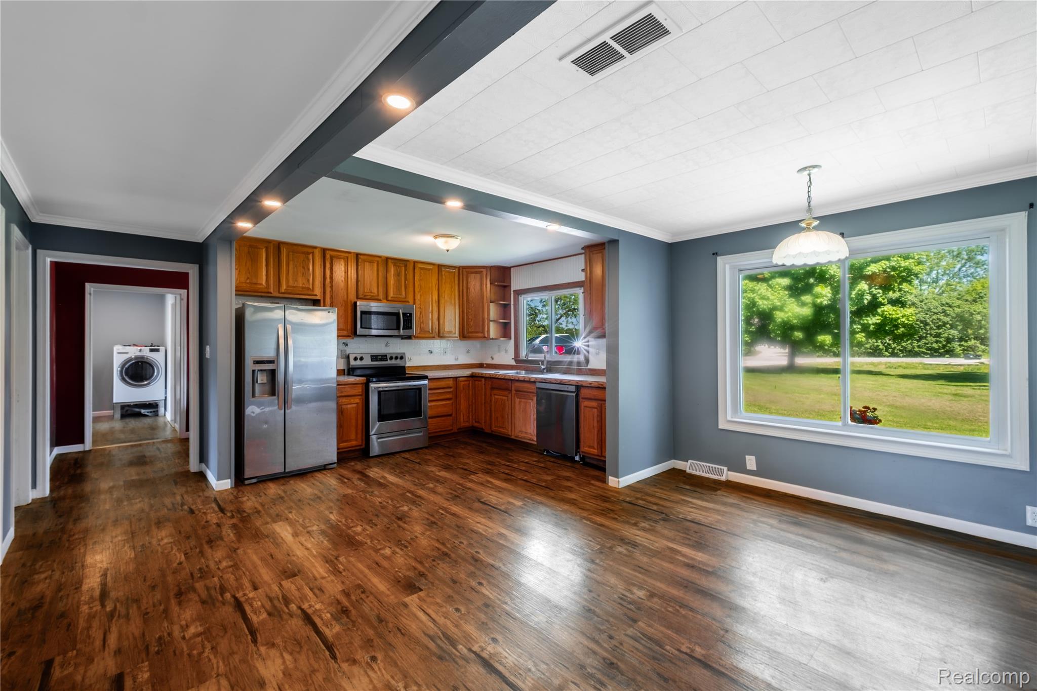 12238 Jennings Road Linden, MI 48451 - Photo 13 of 33 Open-concept kitchen and dining area featuring wood-finish flooring, stainless steel appliances, light wood cabinetry, a large window, and recessed lighting