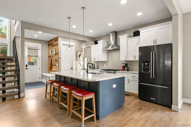 a kitchen with stainless steel appliances a refrigerator a sink dishwasher a dining table and chairs with wooden floor