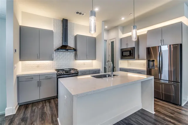 a kitchen with stainless steel appliances granite countertop a sink a stove a refrigerator and a oven