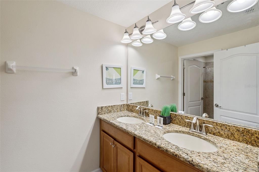 8957 Sugar Palm Road Kissimmee, FL 34747 - Photo 14 of 68 a bathroom with a granite countertop sink a large mirror and a light fixture