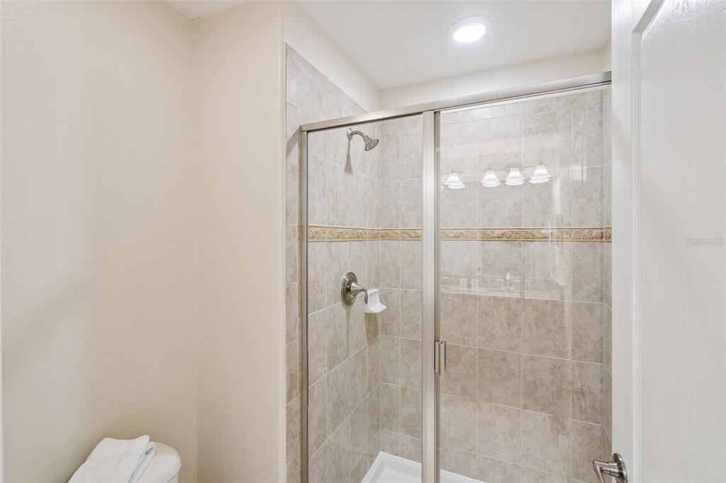 8957 Sugar Palm Road Kissimmee, FL 34747 - Photo 15 of 68 a bathroom with a glass shower door