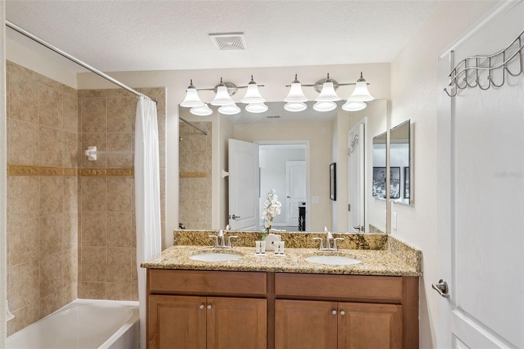 8957 Sugar Palm Road Kissimmee, FL 34747 - Photo 17 of 68 a bathroom with a granite countertop sink a mirror and a bathtub