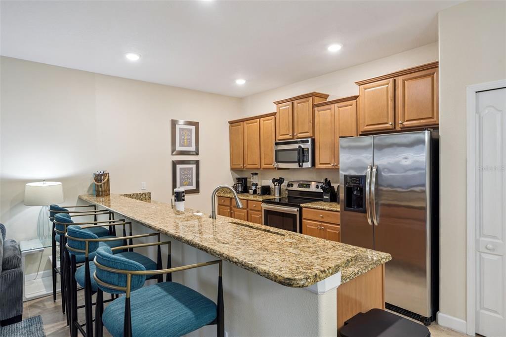 8957 Sugar Palm Road Kissimmee, FL 34747 - Photo 6 of 68 a kitchen with kitchen island granite countertop a table chairs microwave and refrigerator