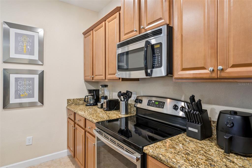 8957 Sugar Palm Road Kissimmee, FL 34747 - Photo 8 of 68 a kitchen with stainless steel appliances granite countertop a stove a sink and a microwave