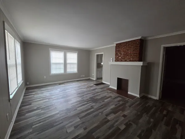 an empty room with windows fireplace and wooden floor