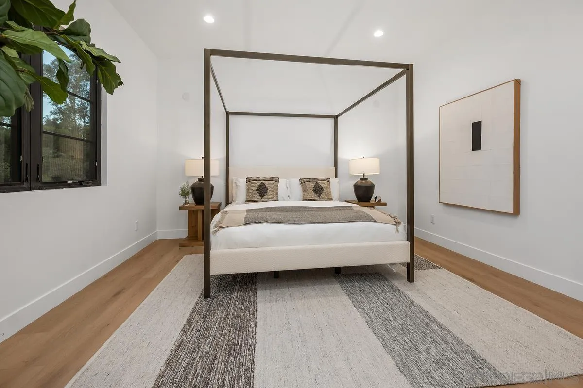 6691-93 Camino Saucito Rancho Santa Fe, CA 92067 - Photo 50 of 55 a spacious bedroom with a bed a mirror and a potted plant