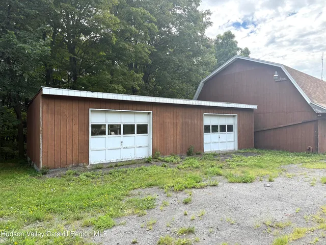 a view of a white house with a yard plants and large trees