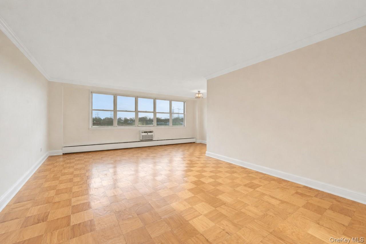 615 Palmer Road, Unit 1004 Yonkers, NY 10701 - Photo 7 of 21 Open, Bright, and spacious living room with crown and base molding, wall unit AC, and large windows upon entering the apartment unit.