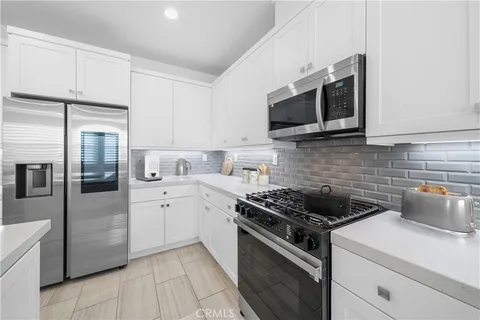 a kitchen with stainless steel appliances white cabinets and a stove top oven
