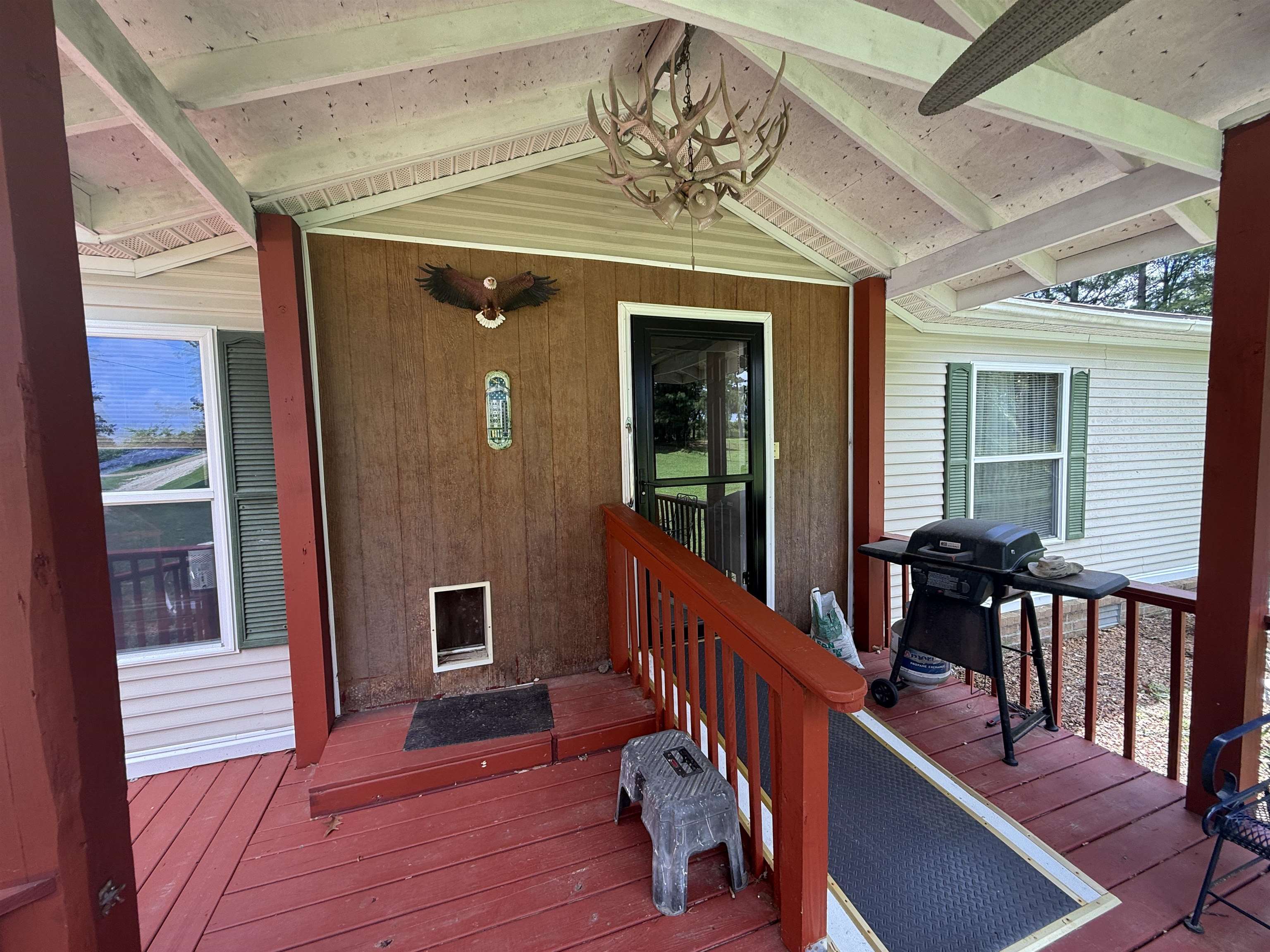 2201 Robert Johnson Road Covington, TN 38019 - Photo 3 of 25 Covered porch featuring a screened entry door, wood-finish siding, and a red-painted wood-plank floor