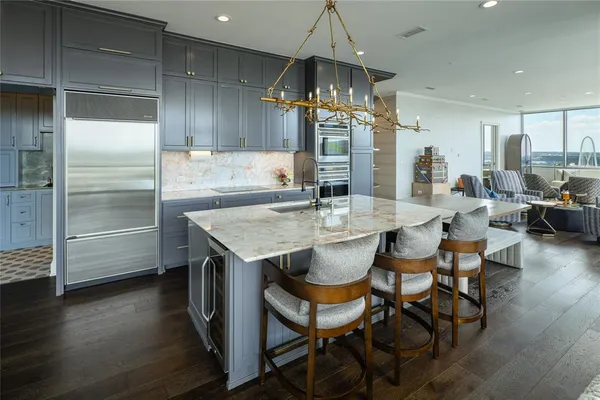 a open kitchen with stainless steel appliances kitchen island granite countertop a table chairs and a refrigerator