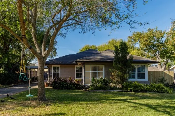 a front view of a house with a yard tree and outdoor seating