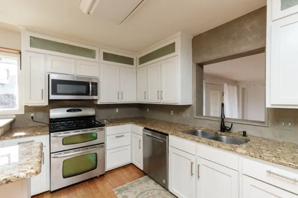 a kitchen with granite countertop a sink cabinets and stainless steel appliances