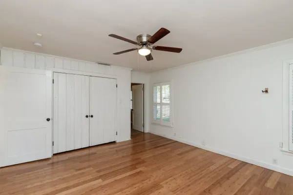 a view of empty room with wooden floor and fan