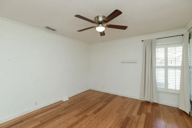 a view of empty room with wooden floor and fan