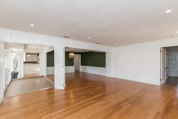 a view of a big room with wooden floor and a kitchen