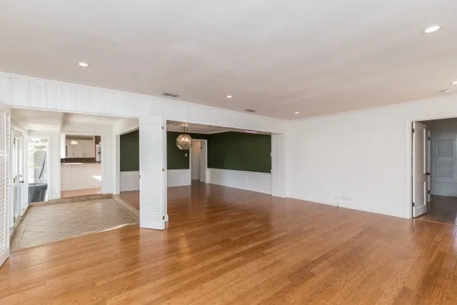 a view of a big room with wooden floor and a kitchen