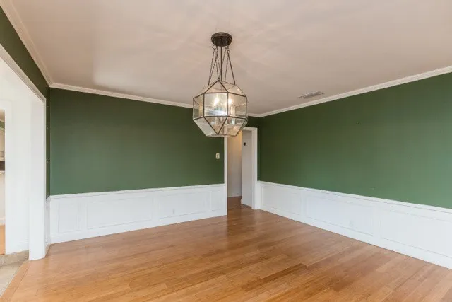a view of a hallway with wooden floor and a chandelier