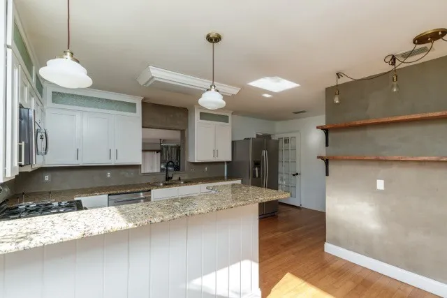 a kitchen with stainless steel appliances granite countertop a sink a refrigerator and a granite counter tops