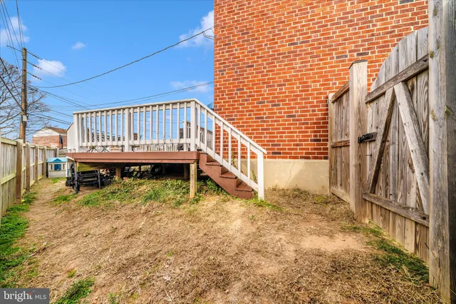 a view of a house with a small yard and wooden deck