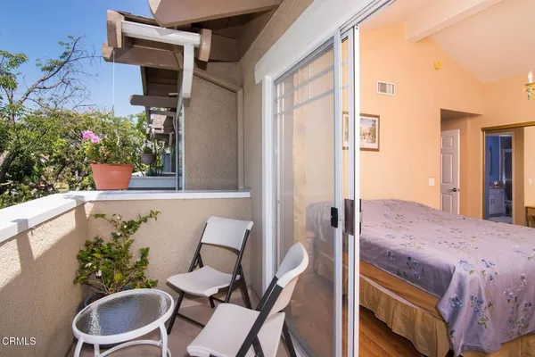 a balcony with table and chairs potted plants