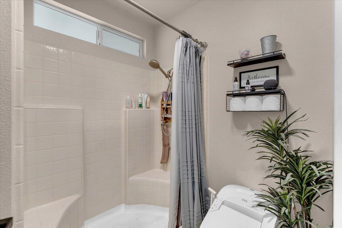 1675 Hominy Way Redding, CA 96003 - Photo 19 of 38 a bathroom with a shower curtain a mirror and a potted plant
