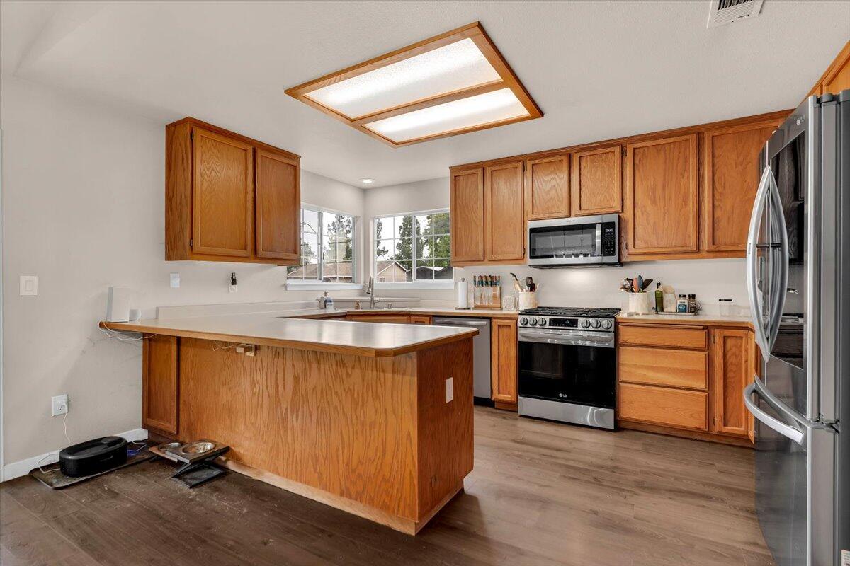1675 Hominy Way Redding, CA 96003 - Photo 9 of 38 a kitchen with stainless steel appliances granite countertop a stove top oven a sink dishwasher a refrigerator and a microwave oven with wooden floor
